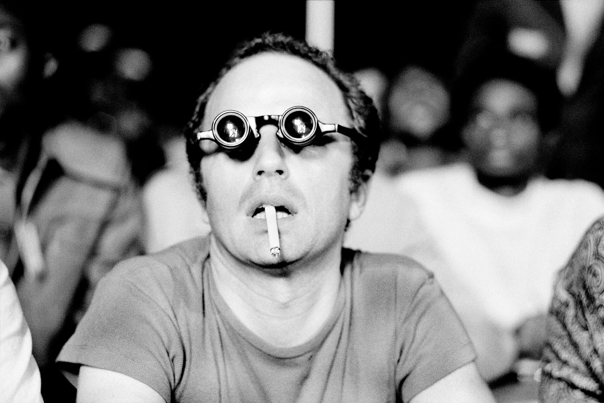 Porträt eines Mannes in einer Filmbrille mit einer Zigarette im Mund, der einen Film sieht